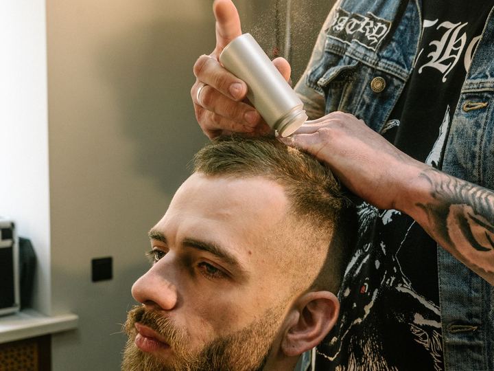 Hombre con el cabello ralo en la parte de arriba mientras le aplican un spray para disimularlo