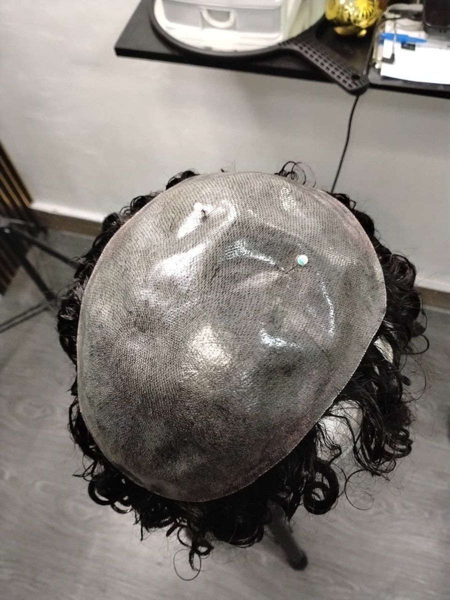 La prótesis de cabello rizado negro, hecha a medida, antes de colocarla